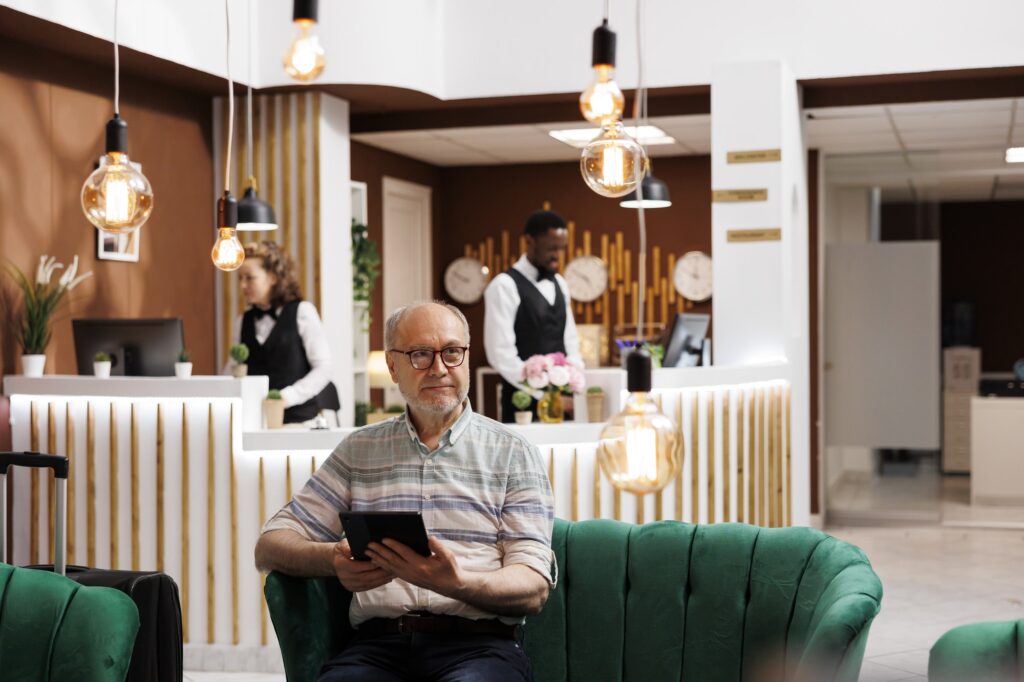 Old man using tablet in hotel lobby